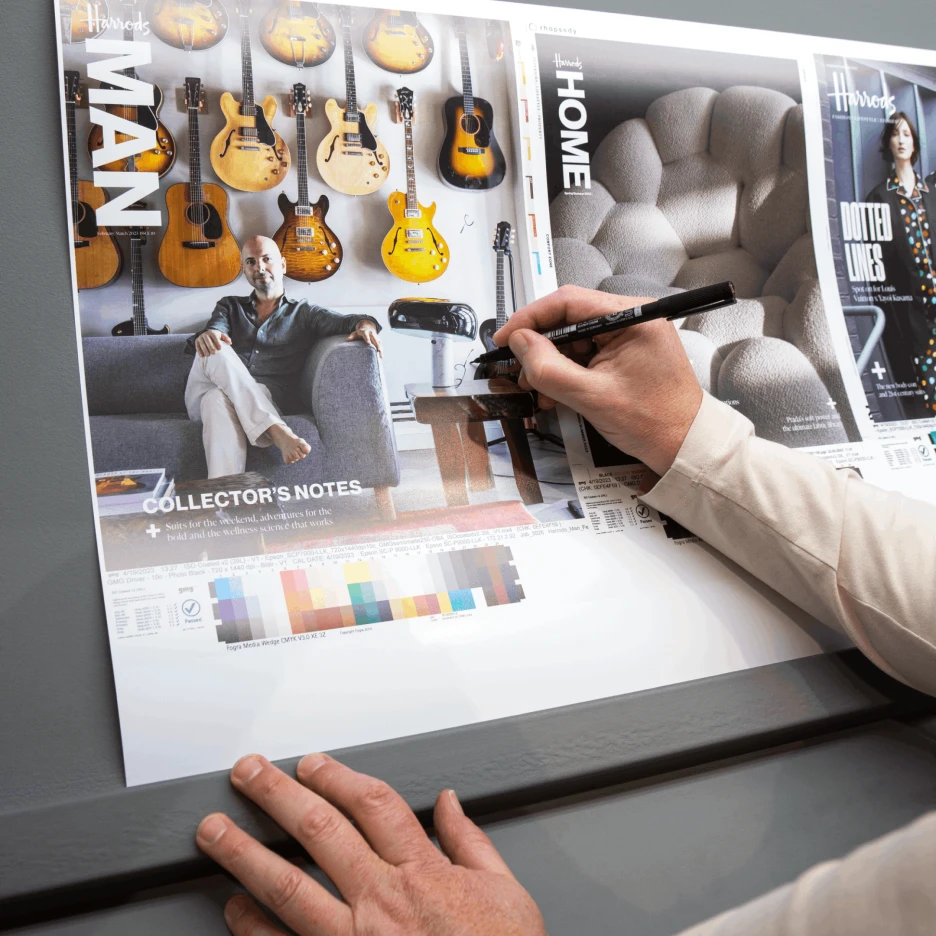 Designer reviewing and marking a printed magazine layout proof with colour calibration bars during the pre-press process