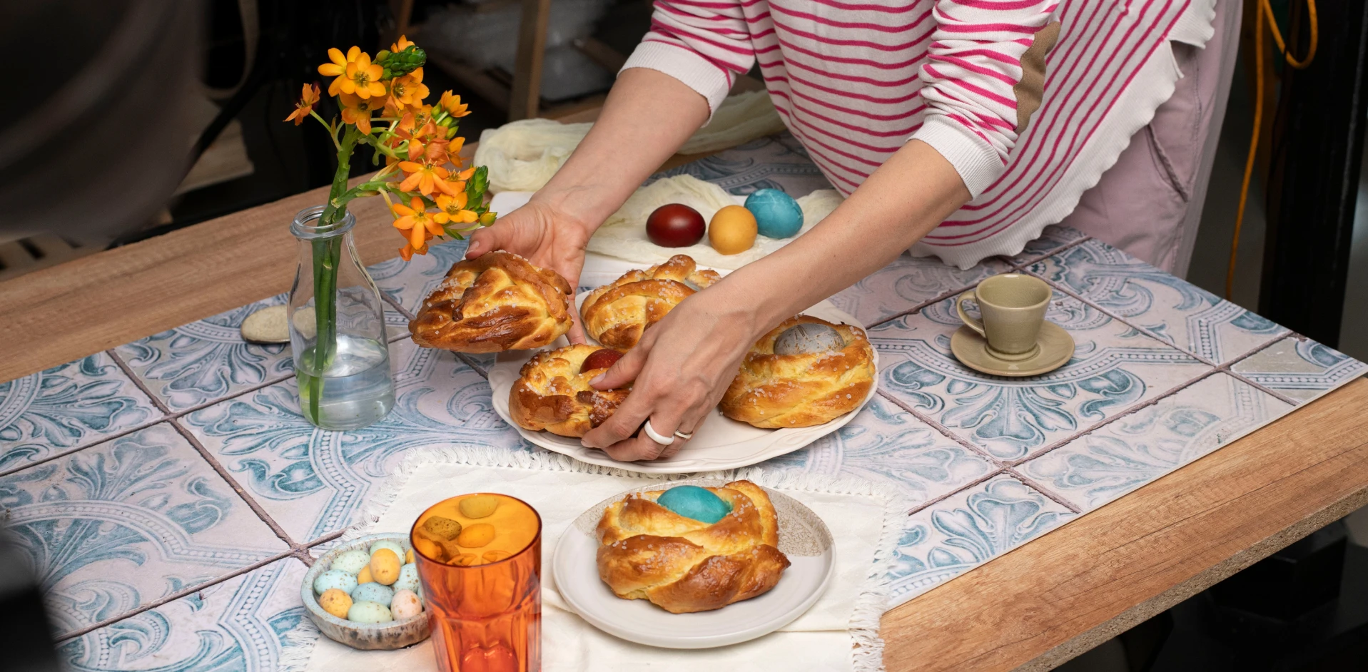 Food stylist arranging freshly baked pastries and colorful eggs on a styled table scene for photography