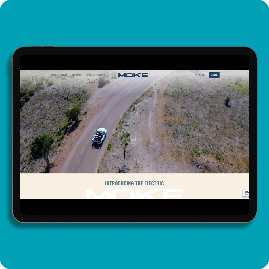 Tablet displaying electric vehicle brand website with promotional video of a car driving on a road