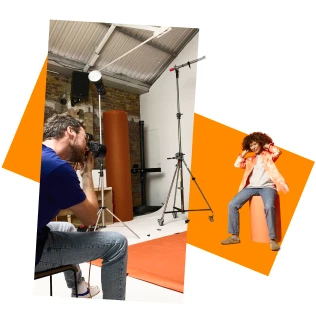 Photographer shooting a model in a professional studio with lighting equipment and orange backdrop.