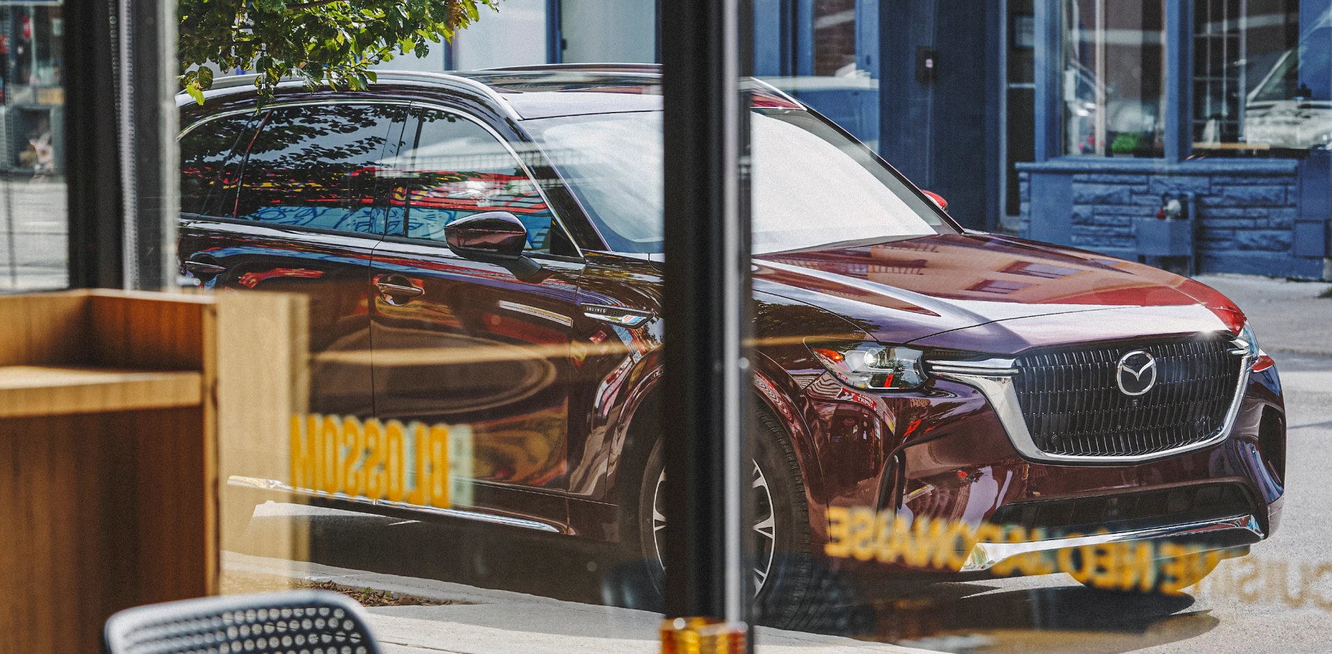 Modern SUV parked on a city street, viewed through a café window, showcasing contemporary automotive design and urban mobility.