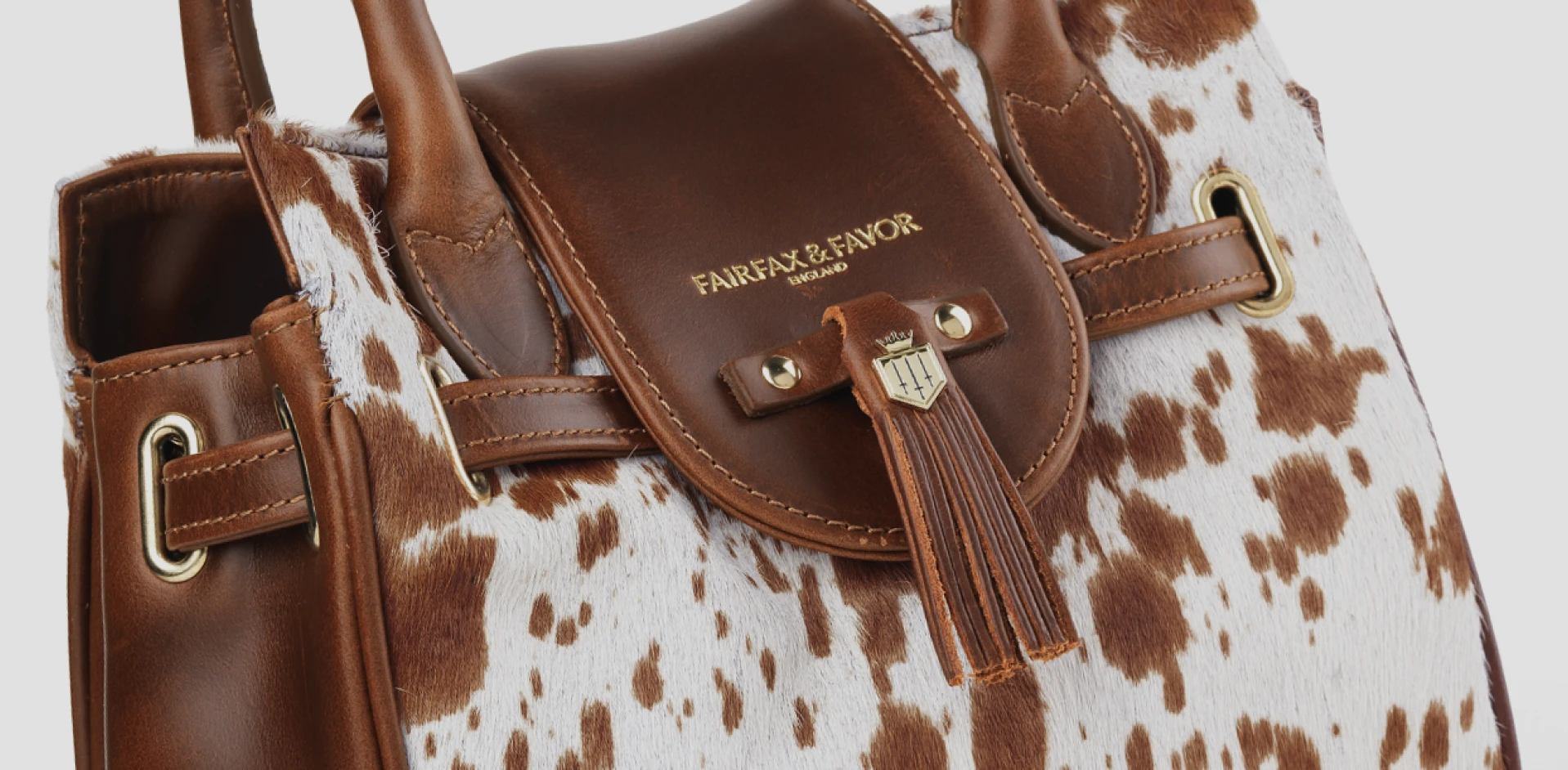 Close-up of a brown leather handbag with a patterned hair-on hide finish and gold hardware details.